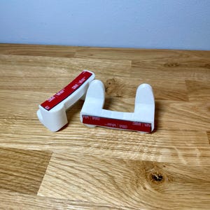 Pan lid mounts shown with installation tape on a wooden desk with grey background