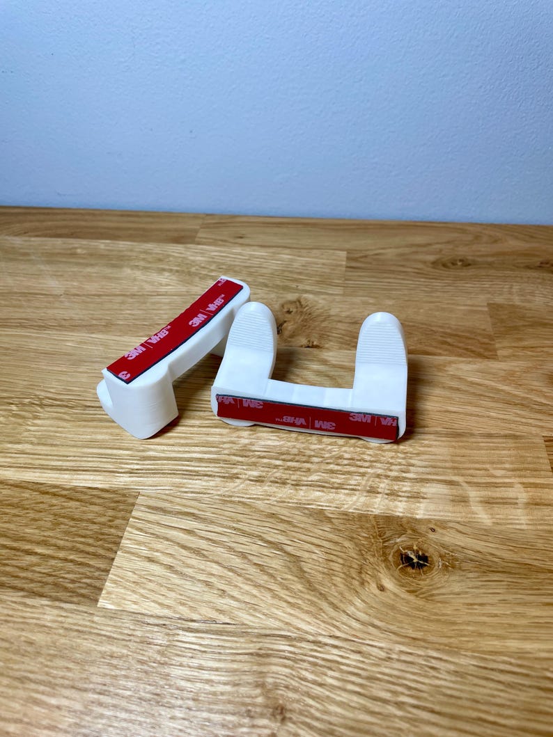 Pan lid mounts shown with installation tape on a wooden desk with grey background