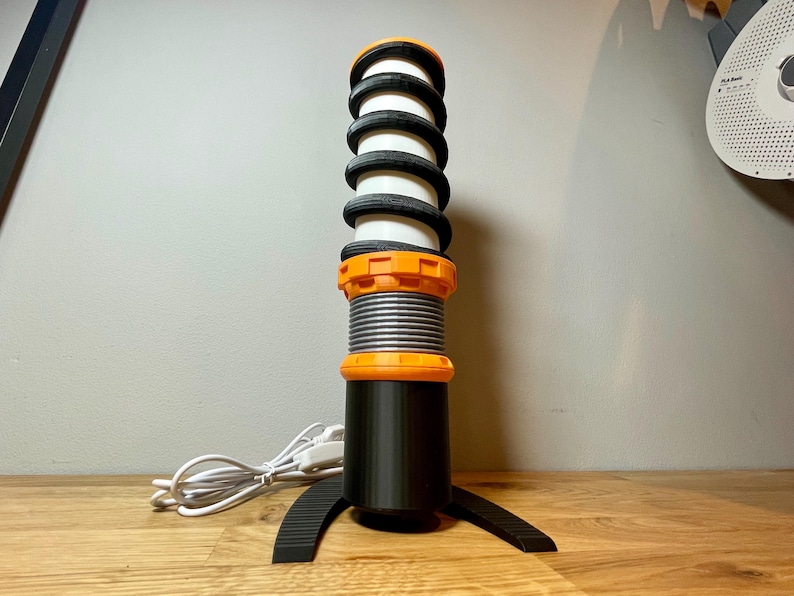 Op de afbeelding: Een zwarte en oranje desktopmicrofoon met een veerachtig ontwerp en een basis met een gebogen vorm.