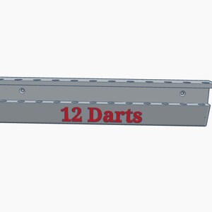 Puede incluir: Un soporte gris para dardos con el texto "12 Darts" en rojo. El soporte tiene dos filas de agujeros para dardos y est&aacute; dise&ntilde;ado para montarse en la pared. El soporte est&aacute; hecho de un material s&oacute;lido.