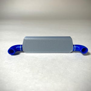 May include: A small, rectangular, gray object with blue, curved tubes extending from each end. The gray body has a textured surface. The blue tubes have a white stripe. The object is likely a component or part of a larger system.