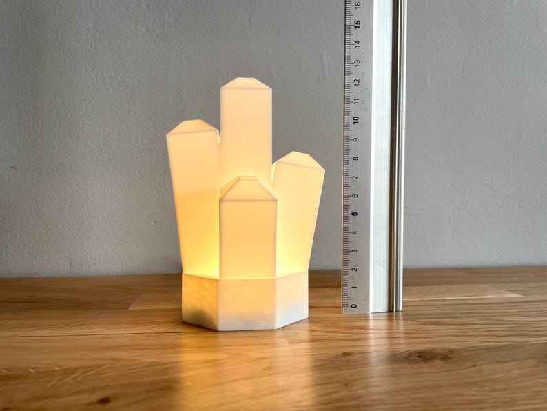 Pu&ograve; includere: Una lampada bianca a forma di cristallo con una luce calda e brillante. La lampada &egrave; realizzata in un materiale bianco liscio e ha un design geometrico.