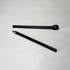 May include: Two black tools are displayed against a white background. One tool is a long, thin rod with a circular end. The other is a similar rod with a pointed tip. Both tools appear to be made of plastic.