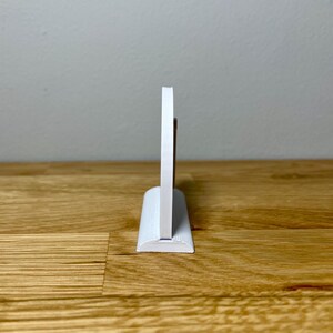 Wedding table numbers in white standing up on a wooden desk with grey background. Side profile