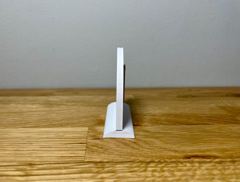 Wedding table numbers in white standing up on a wooden desk with grey background. Side profile