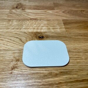 May include: A white, round, slightly raised coaster with a smooth surface.