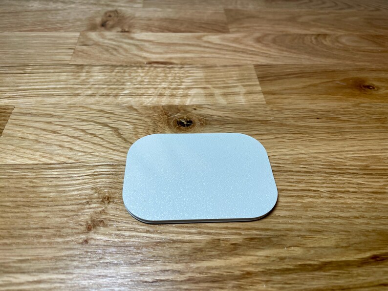 May include: A white, round, slightly raised coaster with a smooth surface.