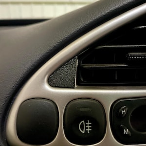 Dashboard of a ford puma showing the small black triangle cover plate next the the air vent.