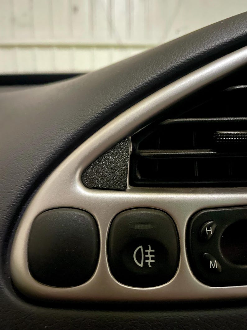 Dashboard of a ford puma showing the small black triangle cover plate next the the air vent.