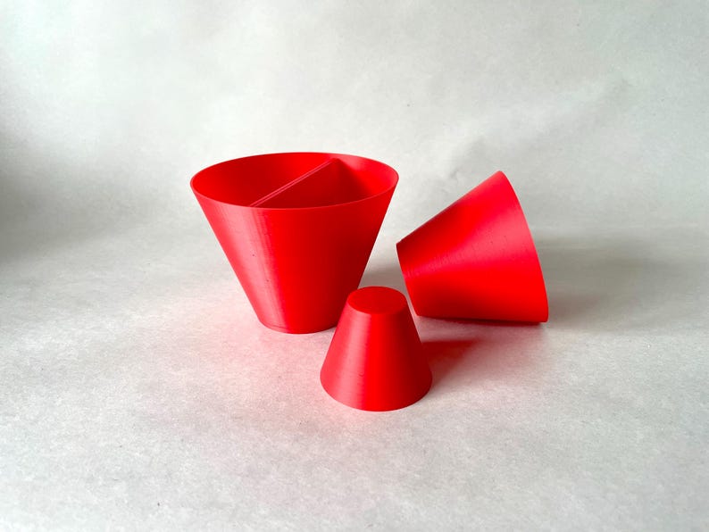 May include: Three bright red, cone-shaped objects are arranged on a light background. One is a large, divided cone, another is a smaller cone, and the third is a cone lying on its side. The objects appear to be 3D printed.