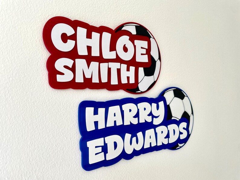 May include: Two personalized name tags with soccer ball accents. One is red with "CHLOE SMITH" in white, the other is blue with "HARRY EDWARDS" in white. Both have a soccer ball design.