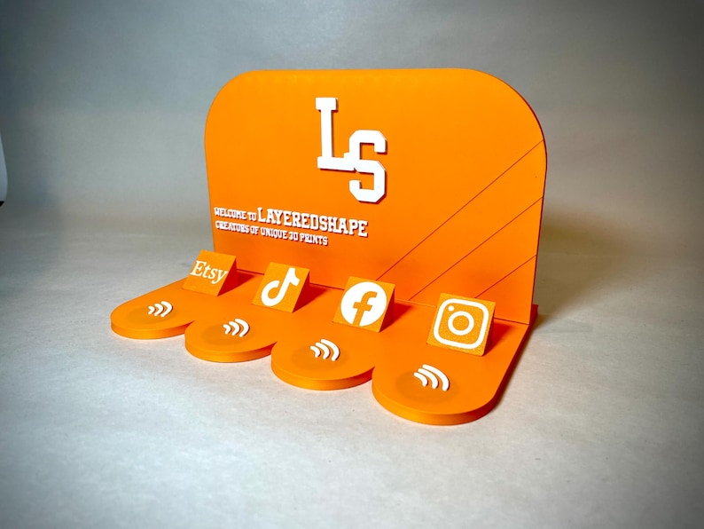May include: Orange display stand with white text and social media icons for Etsy, TikTok, Facebook, and Instagram. The stand features the text "WELCOME TO LAYEREDSHAPE CREATORS OF UNIQUE 3D PRINTS" and the initials "LS".