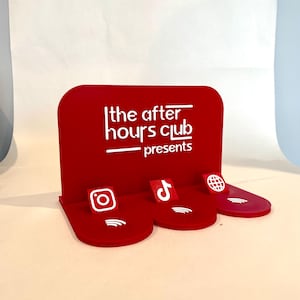 May include: A red display stand with the text "the after hours club presents" in white. The stand has three platforms with social media icons: Instagram, TikTok, and a globe.