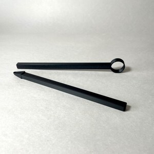 May include: Two black tools are displayed against a white background. One tool is a long, thin rod with a circular loop at the end. The other tool is a long, thin rod with a pointed tip. Both tools appear to be made of a matte black material.