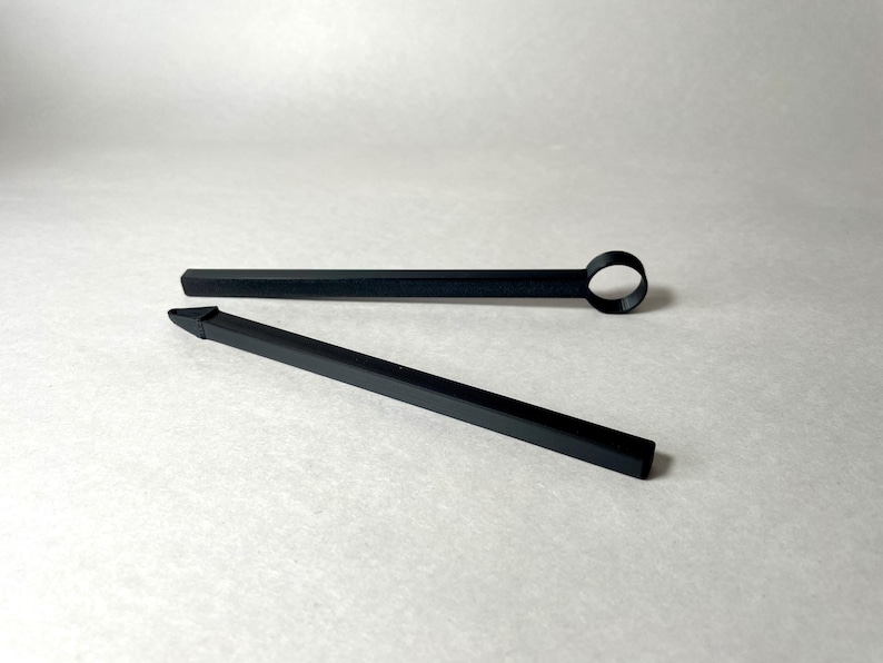 May include: Two black tools are displayed against a white background. One tool is a long, thin rod with a circular loop at the end. The other tool is a long, thin rod with a pointed tip. Both tools appear to be made of a matte black material.