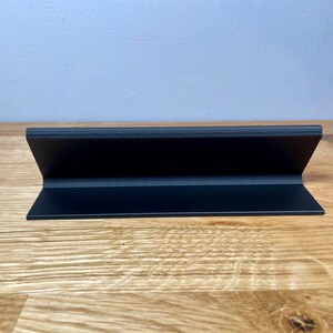 name plaque / plate with a teachers name and best teacher ever! text on the front. Black with bronze text on a wooden desk with grey background