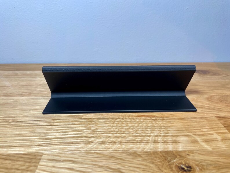name plaque / plate with a teachers name and best teacher ever! text on the front. Black with bronze text on a wooden desk with grey background