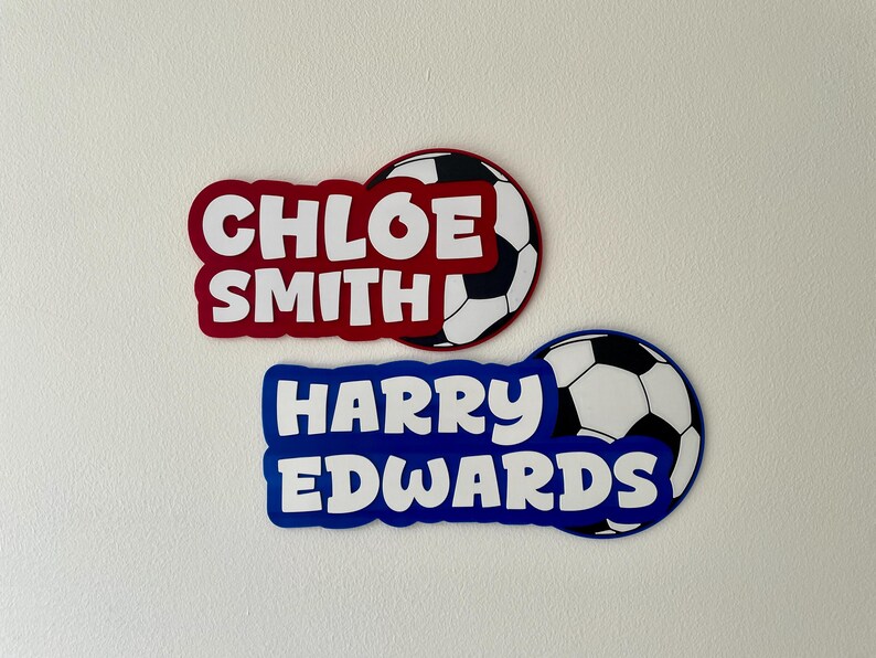 May include: Two personalized soccer-themed name tags. One is red with the name "CHLOE SMITH" and a soccer ball graphic. The other is blue with the name "HARRY EDWARDS" and a soccer ball graphic.