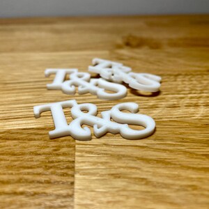 Drinks topper in white on a wooden desk. Initials T&S