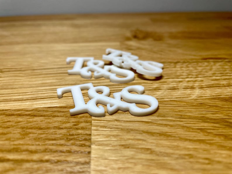 Drinks topper in white on a wooden desk. Initials T&S