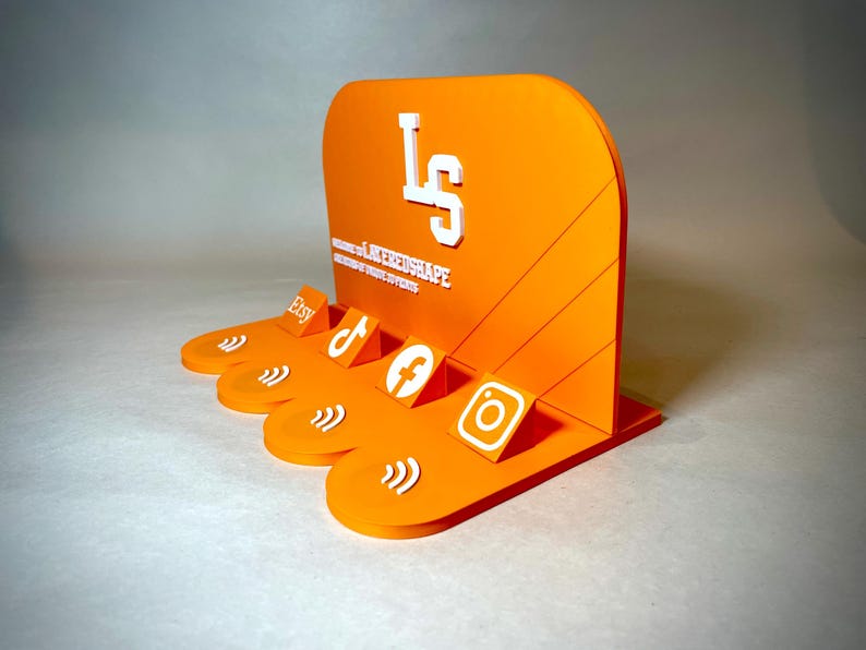 May include: An orange acrylic display stand with white text and social media icons. The stand features the Etsy, TikTok, Facebook, and Instagram logos. The text on the stand reads "LS" and "LAYEREDSHAPE".