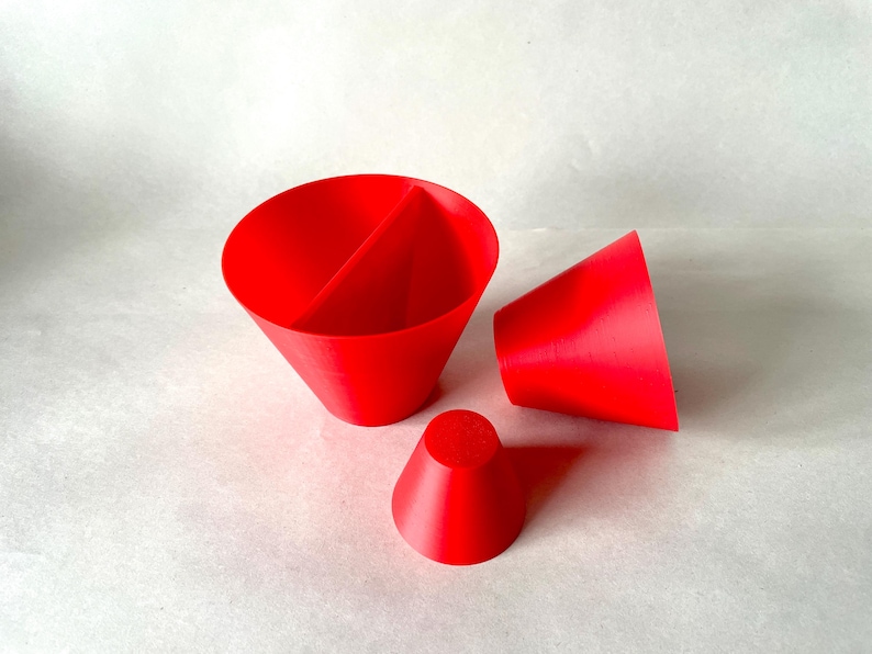 May include: Bright red 3D-printed objects, including a large cone divided into two sections, a smaller cone, and a truncated cone. The objects are arranged on a white surface, showcasing their geometric shapes and vibrant color.