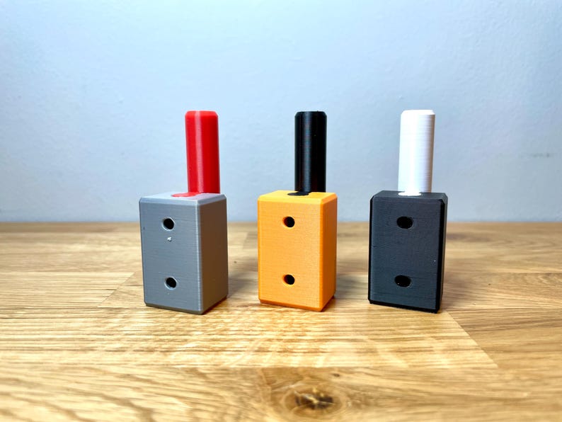 Op de afbeelding: Drie kleine, rechthoekige dozen met verschillende gekleurde bovenkanten. De doos links heeft een rode bovenkant, de middelste doos heeft een oranje bovenkant en de doos rechts heeft een zwarte bovenkant.