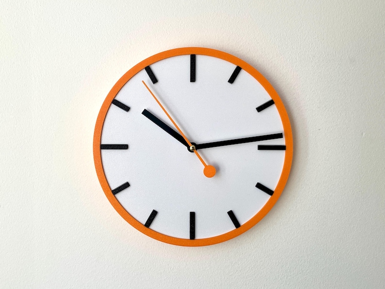May include: A round orange clock with black hour and minute hands and black markings for the hours. The clock face is white.