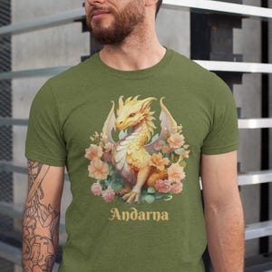 May include: A green t-shirt with a yellow dragon surrounded by pink and white flowers. The text "Andarna" is printed below the dragon.