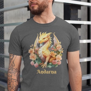 May include: A heather gray t-shirt with a yellow dragon surrounded by pink and white flowers. The text "Andarna" is printed below the dragon.
