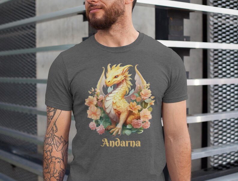 May include: A heather gray t-shirt with a yellow dragon surrounded by pink and white flowers. The text "Andarna" is printed below the dragon.