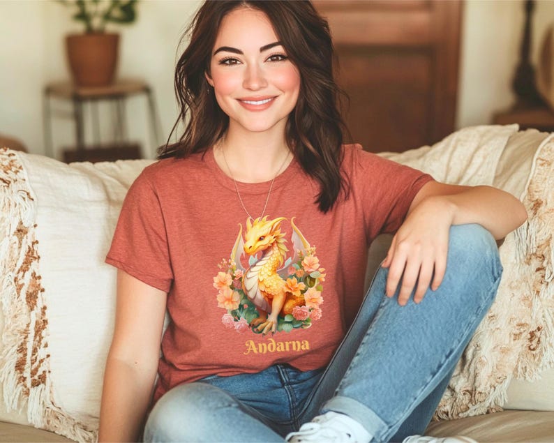 May include: A red t-shirt with a yellow dragon and floral design. The text "Andarna" is printed below the dragon.