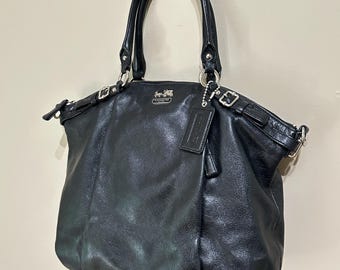 Bolso tote/bandolera Coach de piel negra con herrajes plateados.