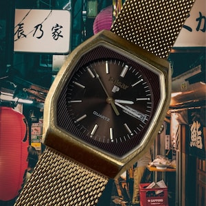 May include: A gold-toned Pulsar quartz wristwatch with a brown face and a mesh metal band. The watch face has white hands and markers, a date window, and the word "Pulsar" printed in white.