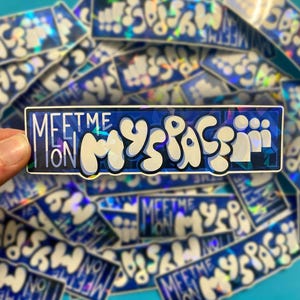 May include: A rectangular holographic sticker featuring the text "MEETME ON MYSPACE" in a bold, white, bubble-style font. The background of the sticker is a dark blue with a geometric, faceted pattern that reflects light with a rainbow effect.