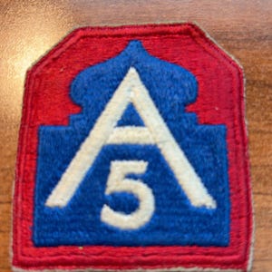 May include: A rectangular embroidered patch with a red border and a blue background. The center features a white letter A positioned above the number 5, with a stylized dome-like shape at the top of the letter A, all rendered in white thread.