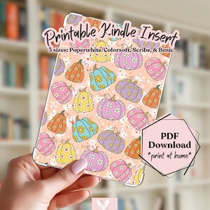 May include: A printable Kindle insert featuring a repeating pattern of colourful pumpkins decorated with white daisies on a light peach background. The text reads Printable Kindle Insert, 3 sizes: Paperwhite/Colorsoft, Scribe, & Basic, and PDF Download *print at home*.
