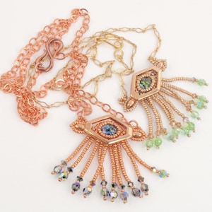 May include: Two copper chain necklaces with a geometric pendant featuring a faceted gemstone. Each pendant has a fringe of copper beads and crystal accents.
