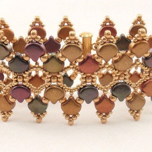 Puede incluir: Un brazalete de cuentas doradas, marrones y moradas con un diseño decorativo de hojas superpuestas. El brazalete está hecho con cuentas pequeñas y redondas y tiene un cierre de broche.