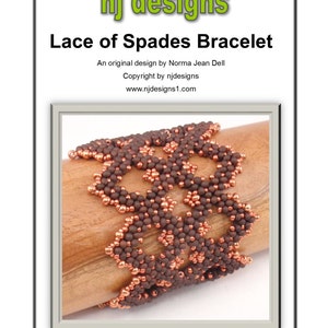 May include: A brown and copper beaded bracelet with a lace-like design. The bracelet is on a wooden surface. "nj designs" and "Lace of Spades Bracelet" are written above the bracelet.