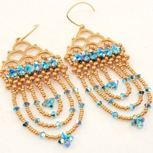 May include: Gold tone earrings with a delicate, intricate design featuring a cascading fringe of blue iridescent beads.