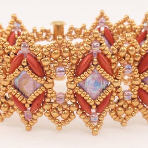 Puede incluir: Un brazalete de cuentas doradas y rojas con un diseño geométrico. El brazalete está hecho con cuentas pequeñas y redondas y cuentas más grandes y rectangulares.