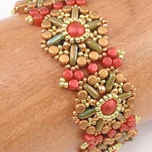 Könnte beinhalten: Ein Armband mit Perlen in einem floralen Design. Das Armband ist aus goldenen, grünen und roten Perlen gefertigt.