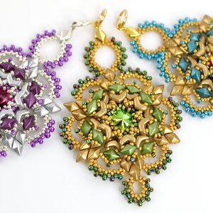 May include: Three beaded earrings with a starburst design. The earrings are made with silver, gold, and teal beads. The center of each earring features a large crystal.