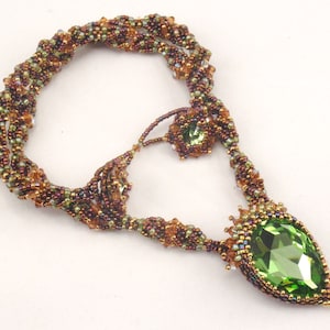 May include: A green and brown beaded necklace with a large green teardrop-shaped crystal pendant.