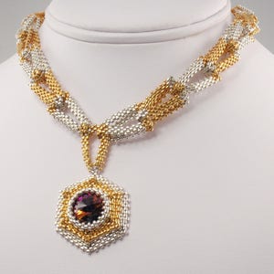 Puede incluir: Un collar de plata y oro con un colgante hexagonal que presenta una gran piedra preciosa púrpura iridiscente.