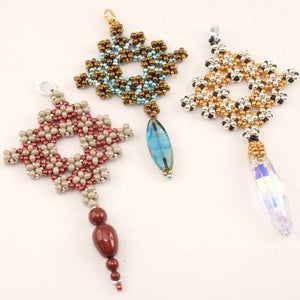 May include: Three beaded pendants with different coloured beads and crystal accents. The pendants are in the shape of a square with a hole in the centre. The beads are brown, gold, and silver.