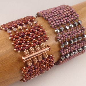 May include: Two beaded bracelets with copper-toned clasps. The bracelet on the left is made with brown and copper beads, while the bracelet on the right is made with purple and black beads.