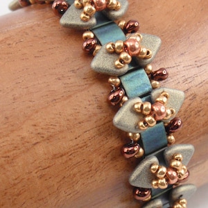 May include: A beaded bracelet with a geometric design. The bracelet is made with silver, gold, and copper beads. The beads are arranged in a pattern of triangles and squares.
