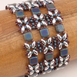 May include: A multi-strand beaded bracelet with a geometric pattern. The bracelet is made with silver, dark blue, and brown beads.